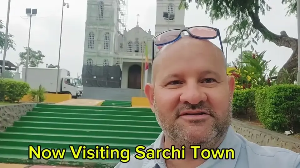 Oscar Calvo talking to the camera in front of the church of Sarchí